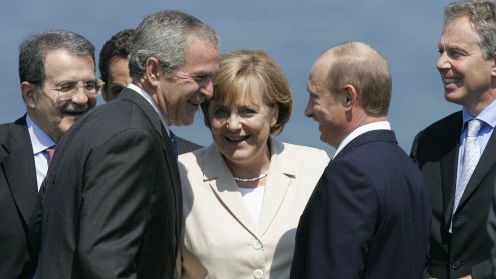 Italian Prime minister Romano Prodi, French President Nicolas Sarkozy (hidden), US President George W. Bush, German Chancellor Angela Merkel, Russian President Vladimir Putin and British Prime Minister Tony Blair share a laugh as they take position for a family picture with other G8 leaders,