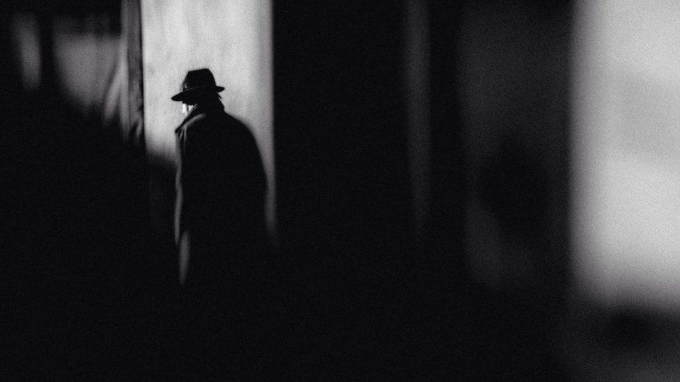 Man in hat walking on street in shadow