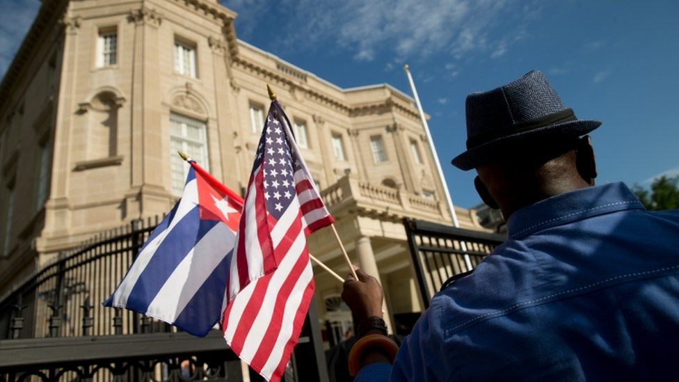Edwardo Clark, a Cuban-American, holds an American flag and a Cuban flag as he celebrates outside the new Cuban embassy in Washington, Monday, July 20, 2015.