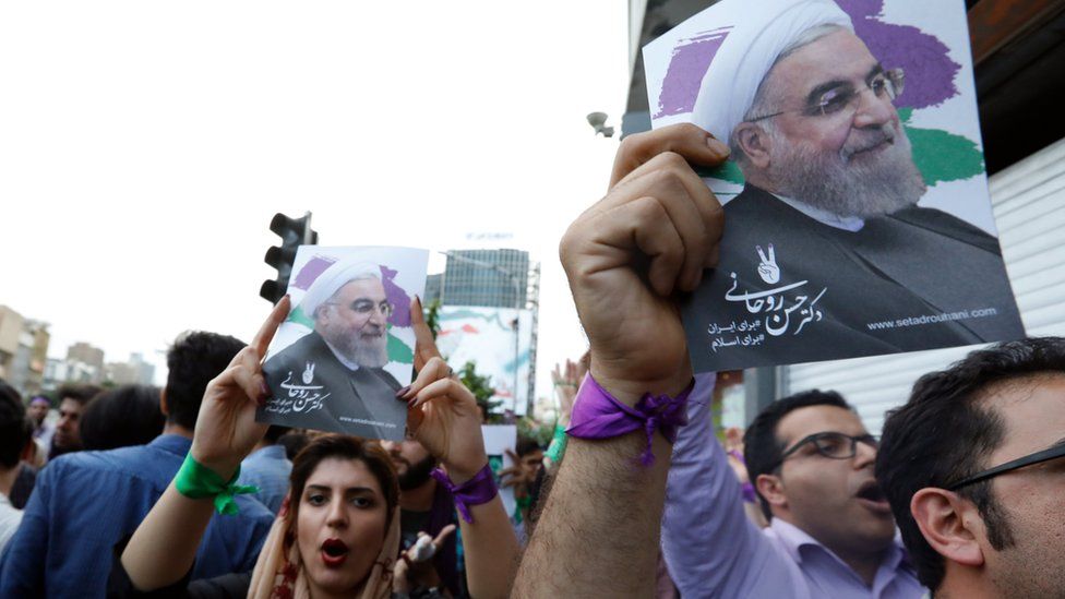 Supporters of Iranian president Hassan Rouhani hold his picture aloft as they celebrate his victory in the presidential elections