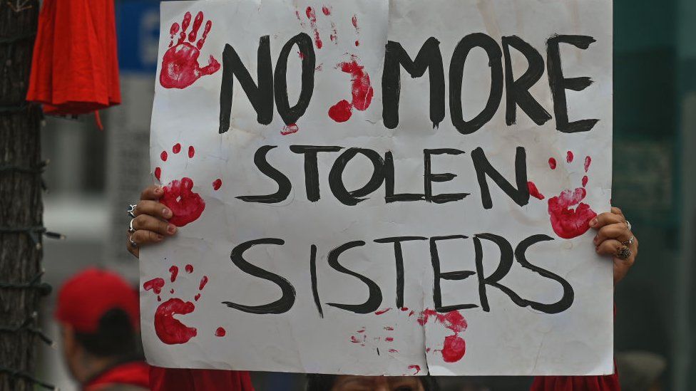 Участники ежегодного марша в честь Дня красного платья в центре Эдмонтона в память о пропавших без вести и убитых женщинах и девочках из числа коренных народов Канады