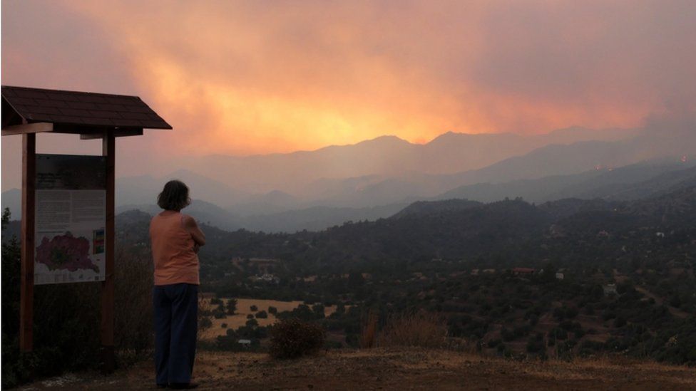 Женщина смотрит на дым и огонь от костра