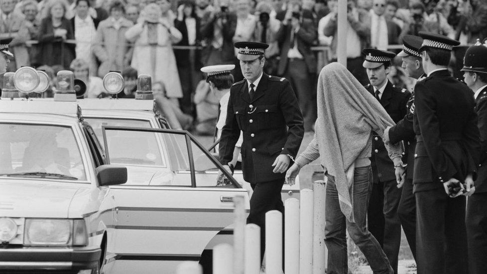 Malcolm Fairley being taken to a police car by officers in 1984