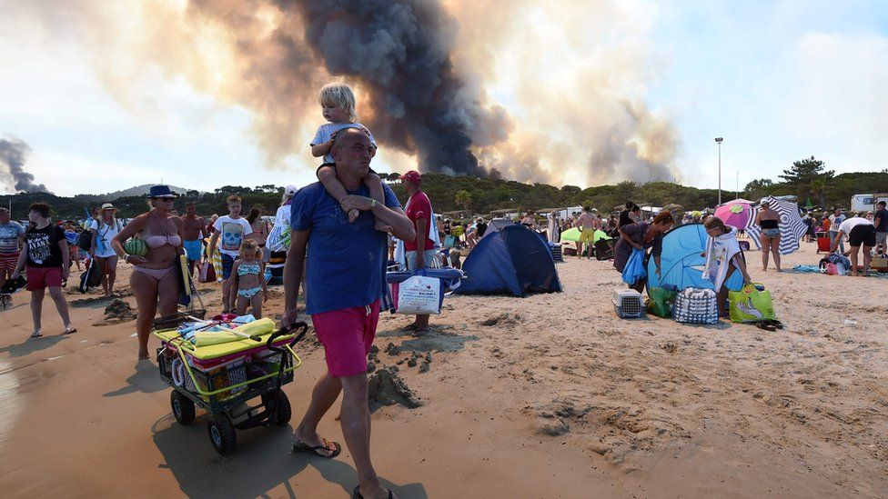 Forest fires in background of beach in Bormes-les-Mimosas, France