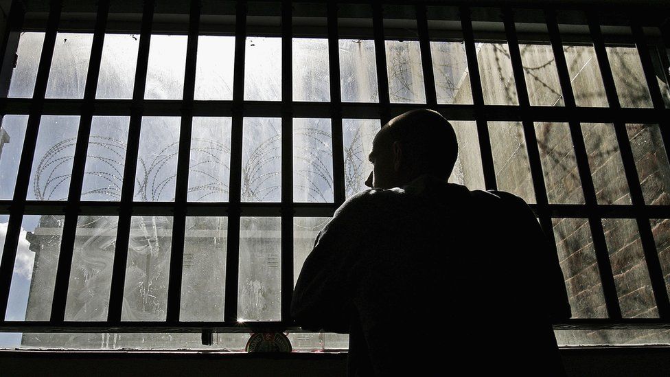 A prisoner looking out of a cell window