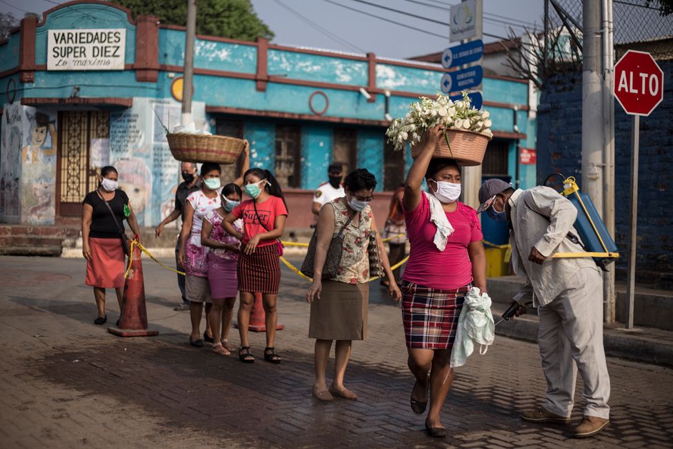Неформальные торговцы дезинфицируют их тела перед выходом на муниципальный рынок в Науисалко, Сонсонате, для продажи своих фруктов и овощей.