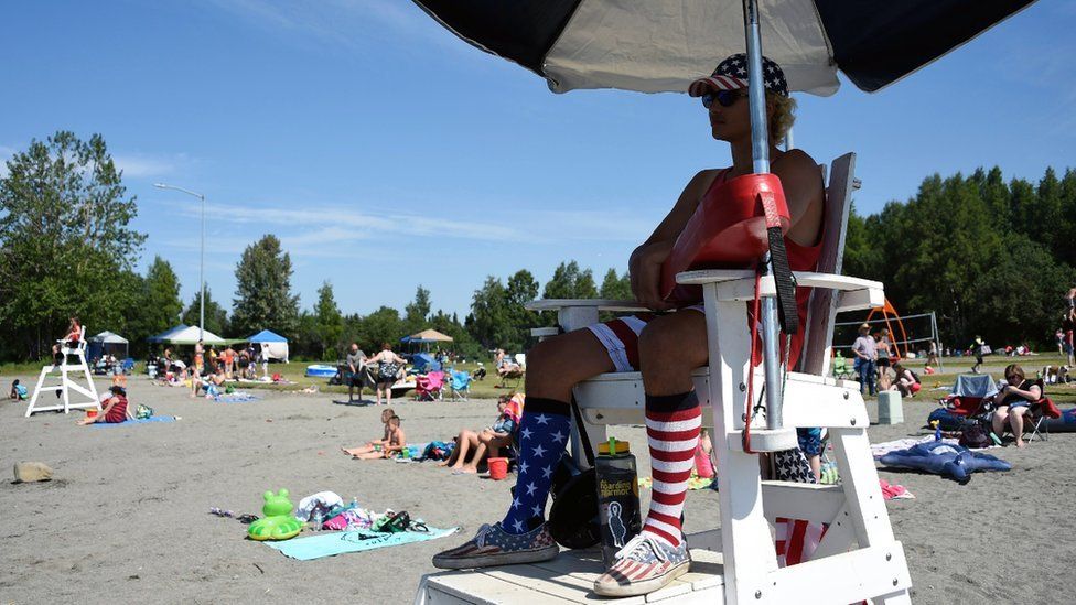A lifeguard watches as people sunbathe at Jewel Lake, Anchorage. Photo: 4 July 2019