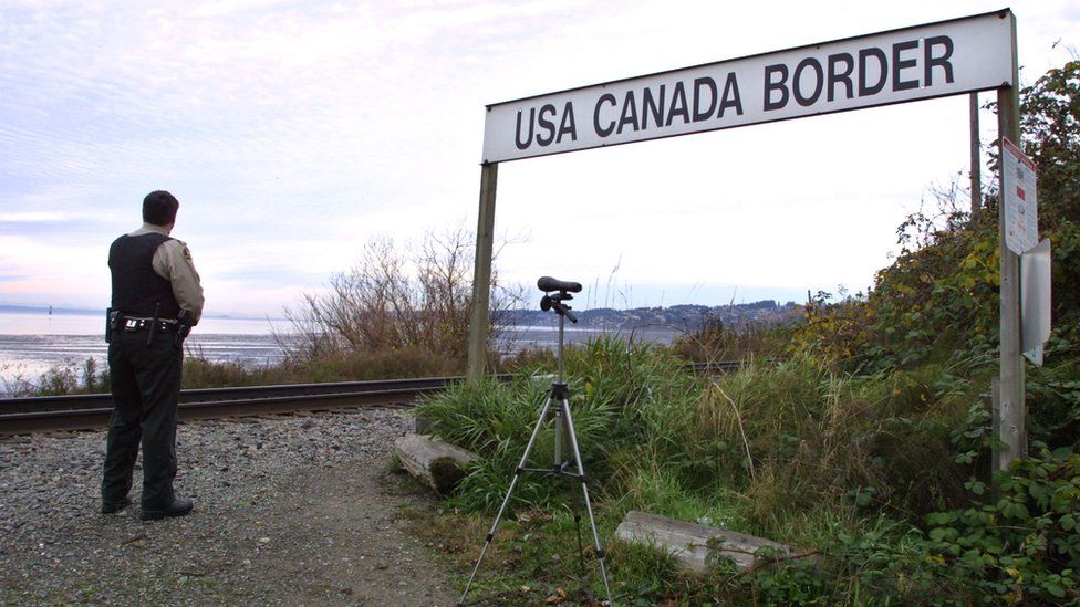 A Canadian Customs and Fisheries officer watches over the U.S.-Canada border between Blaine, Washington and White Rock, British Columbia November 8, 2001 in White Rock, BC. The Peace Arch border crossing is one of the busiest crossings in North America
