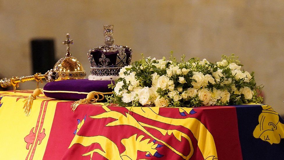 The Queen's coffin covered with the Royal Standard, a wreath, crown, sceptre and orb