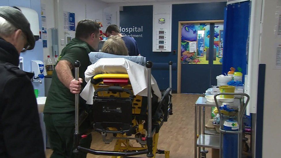 An ambulance worker wheels a patients through Poole Hospital emergency department