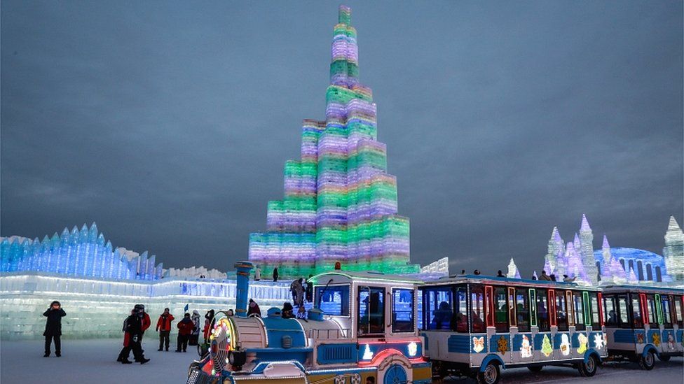 As pessoas visitam esculturas de gelo iluminadas por luzes coloridas no Ice and Snow World em Harbin em 4 de janeiro de 2019