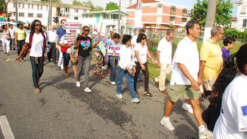 Activists carring placards demaning that "police do your work" march in Guyana
