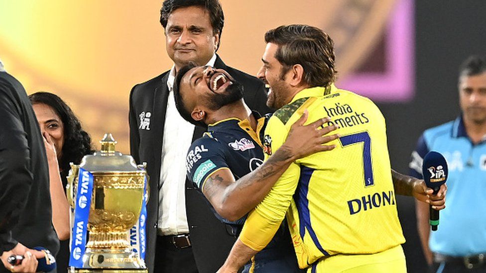 Капитан Chennai Super Kings Махендра Сингх Дхони (справа) и его коллега из Gujarat Titans Хардик Пандья смеются во время жеребьевки перед начало финала IPL