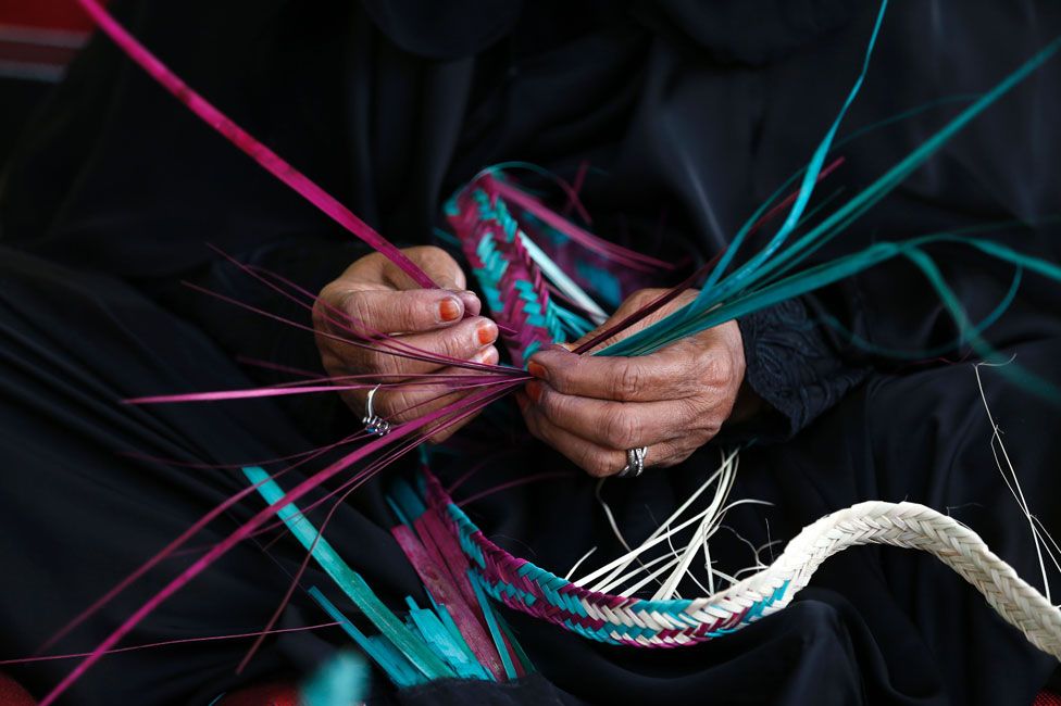 Emirati woman weaving palm fronds