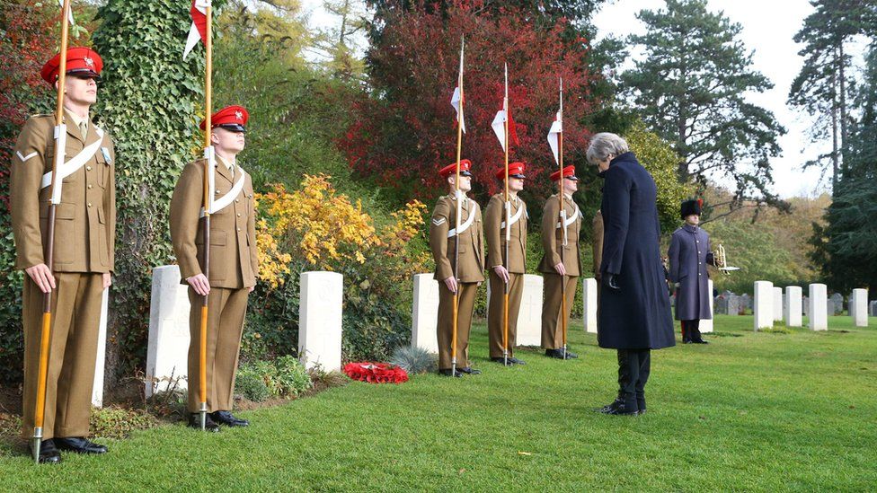 Theresa May bows her head at the grave of Private Ellison