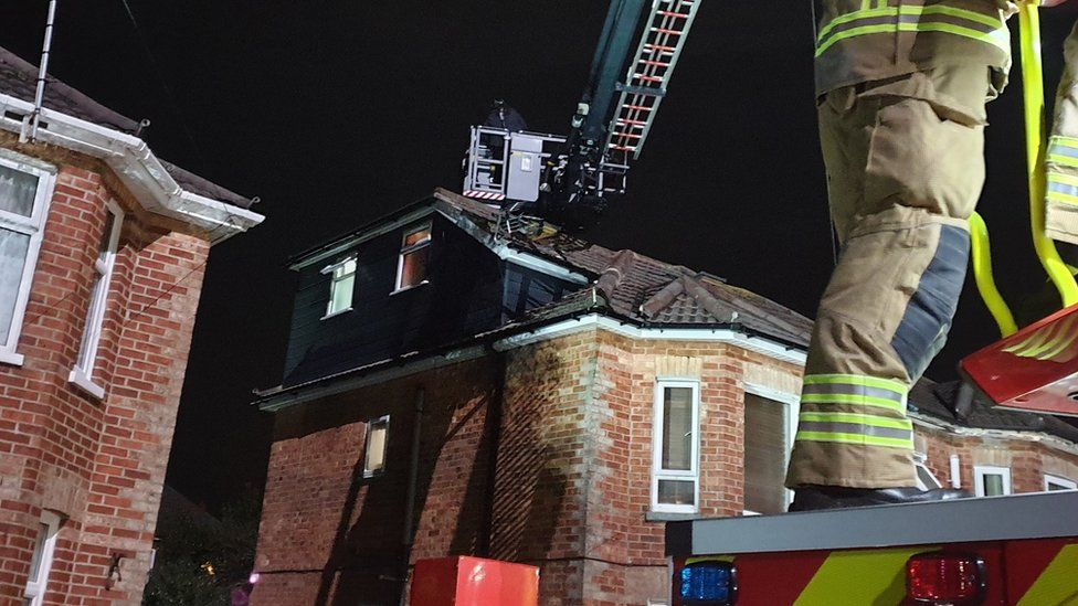 Firefighter operating turntable ladder to reach robbery suspect on roof