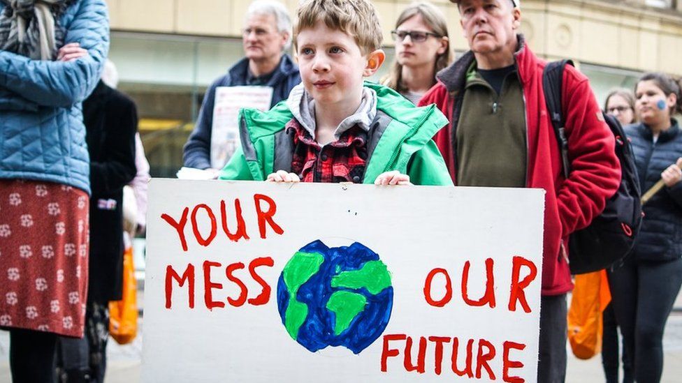 Boy-holds-up-a-banner-at-a-climate-change-protest.