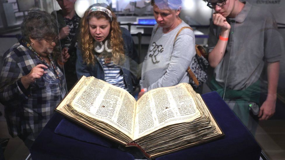 Visitors look at the Codex Sassoon on display at the ANU Museum of the Jewish People in Tel Aviv, Israel (22 March 2023)