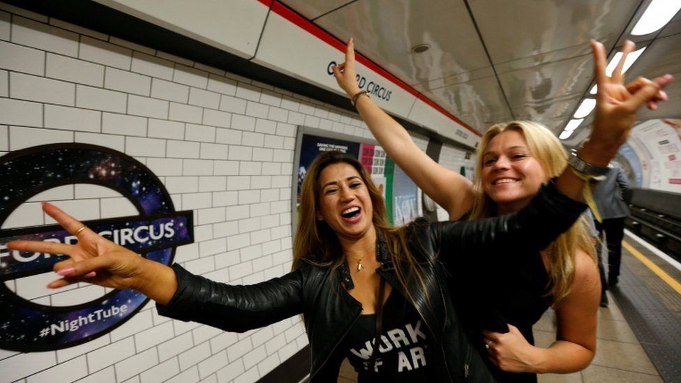 Passengers pose for a photograph as they wait for the Night Tube