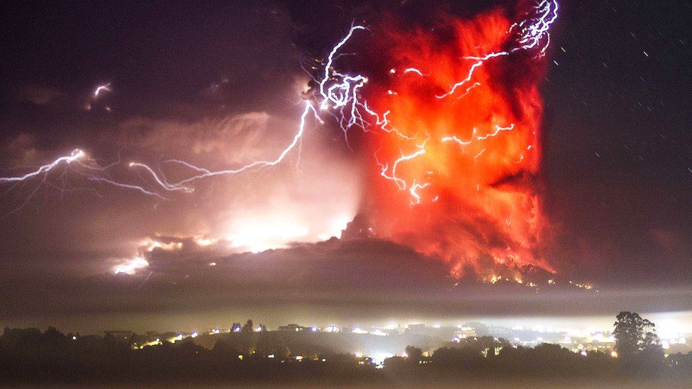 Lightning cracks through a high plume of fire above a volcano.