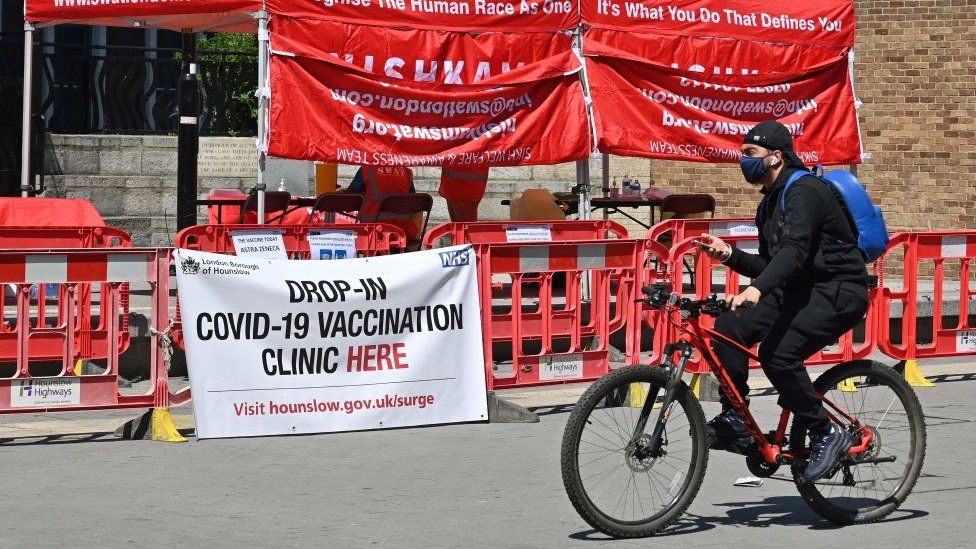 Someone cycling past a vaccine drop-in centre