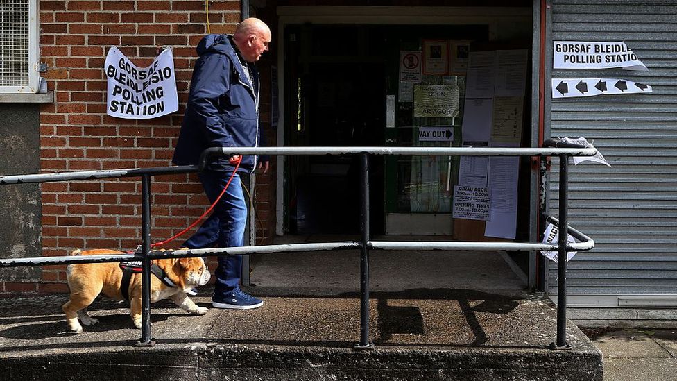 A man with a dog entering a polling station in Wales