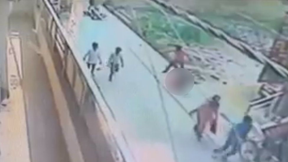 CCTV footage showing the attacker standing over the woman, with the woman blurred from shot