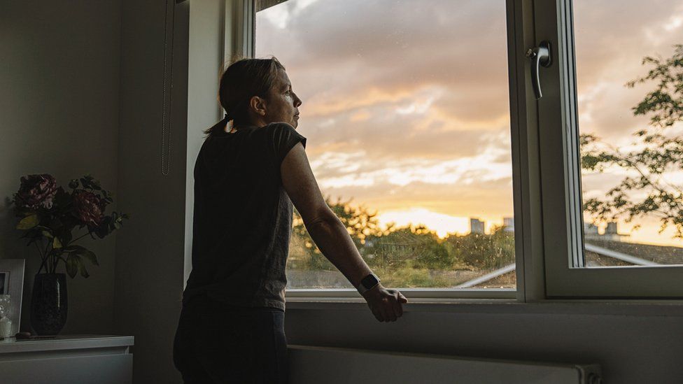 Woman looks through window