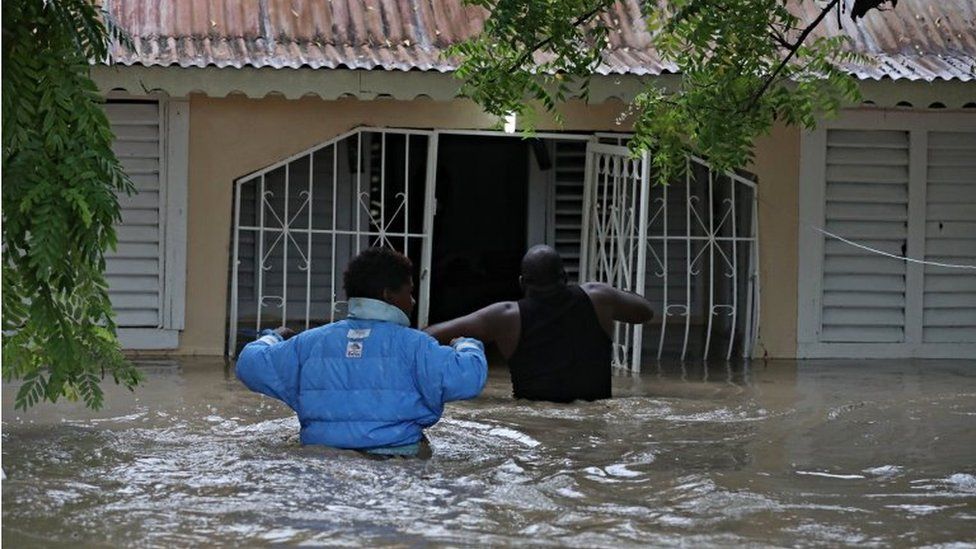 People enter a home during the floods caused by the passage of Storm Laura in Azua, Dominican Republic August 23, 2020.