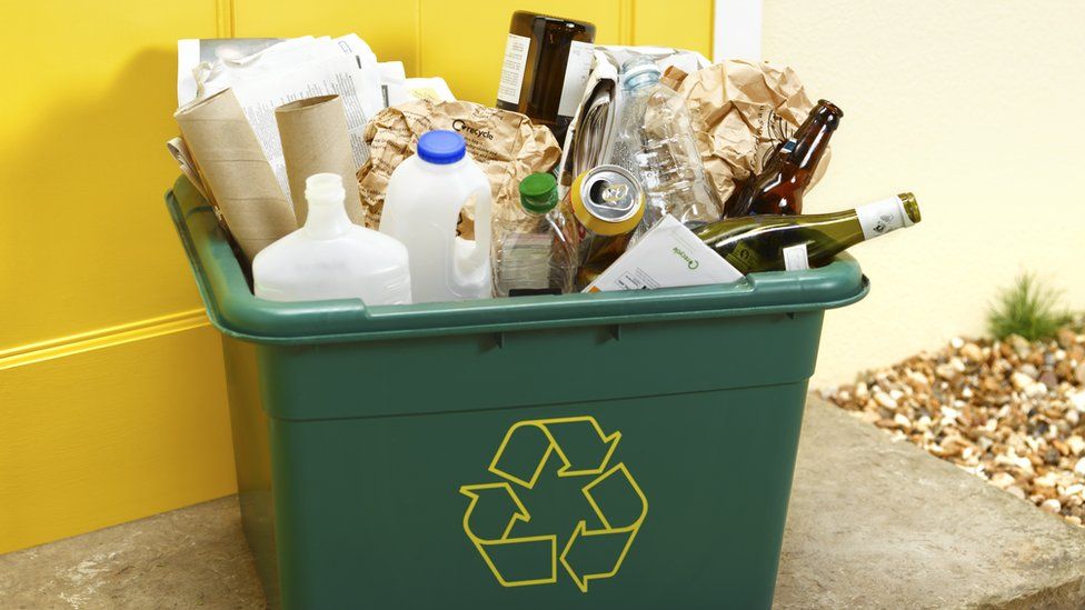 Full household recycling bin - glass bottles, milk bottles and paper wrapping visible