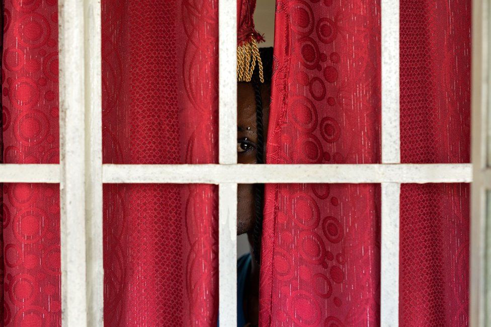 Person peeking through a pair of closed red curtains