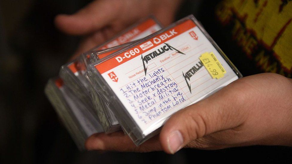 An employee of a music shop holds copies of Metallica's reissued 1982 demo tape in 2015