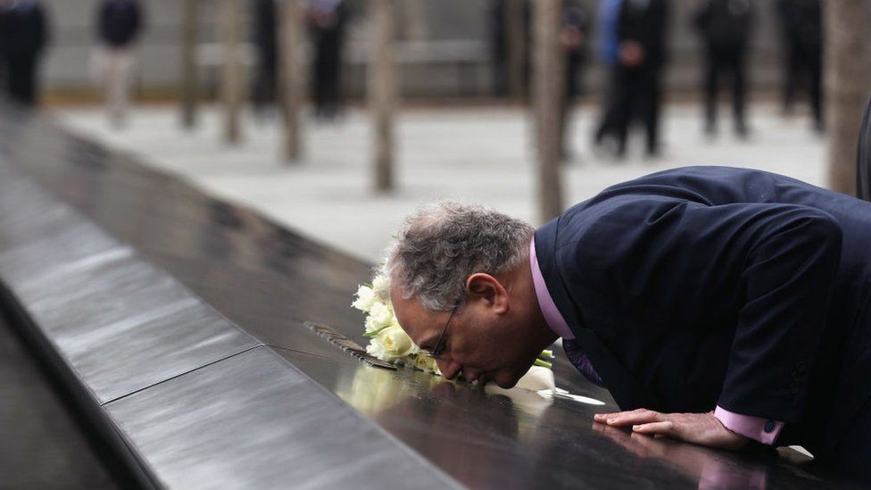 Image shows Charles Wolf kissing the 9/11 memorial in New York