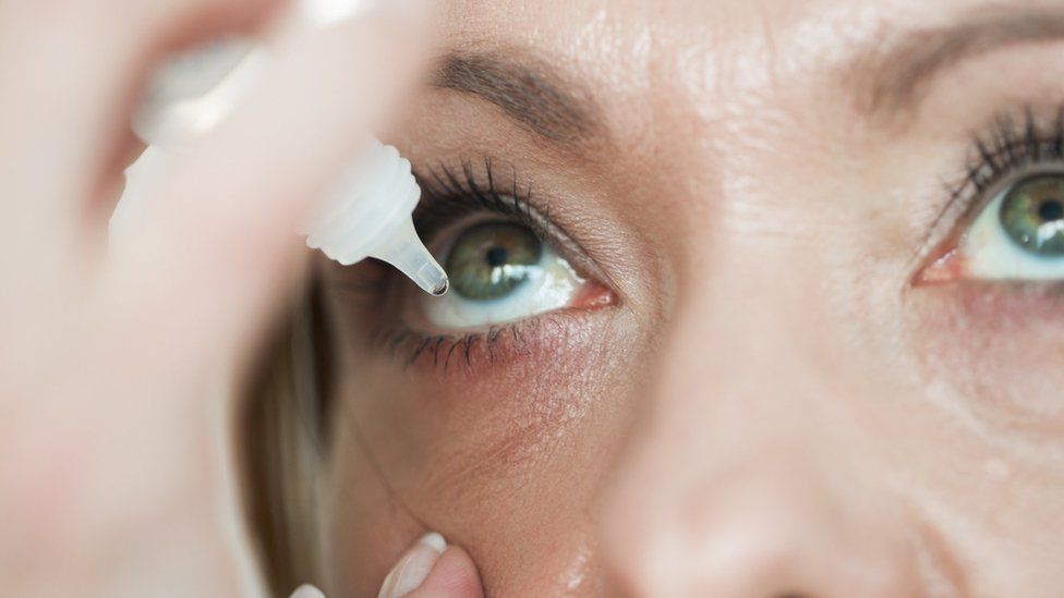 A woman putting eyedrops in