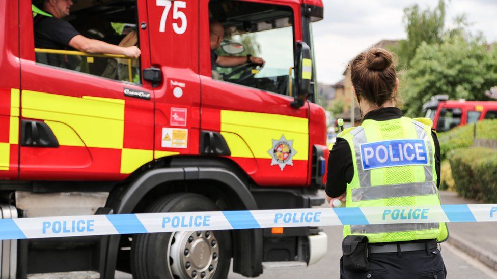 A police officer standing by a fire engine, in Bedford