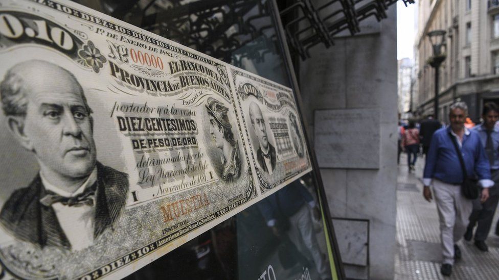 People walk past a bank's branch decorated with images of old Argentine peso bills, in Buenos Aires, on September 26, 2018.