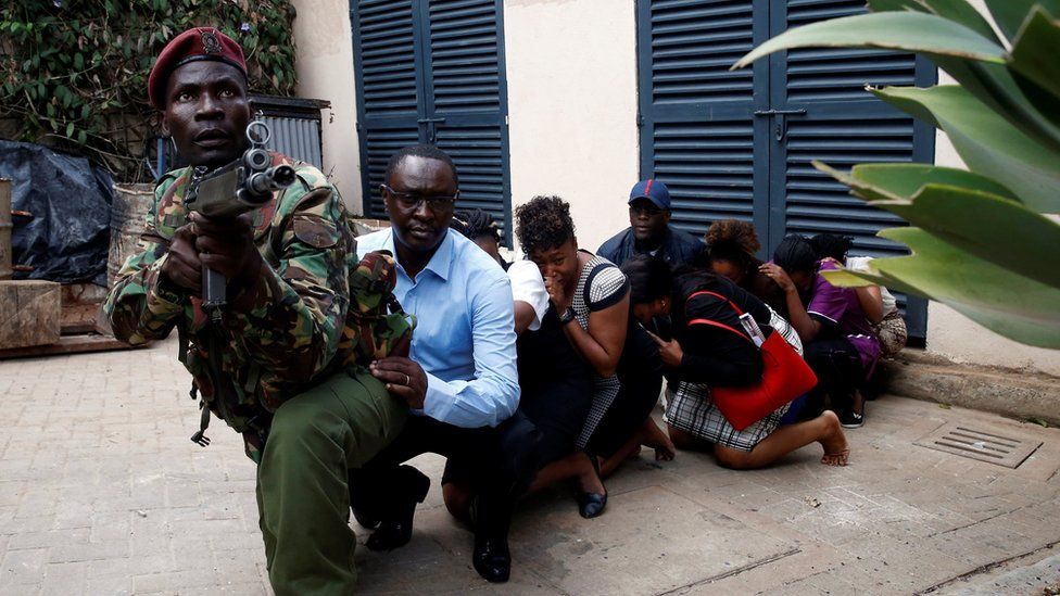 People are evacuated by a member of security forces at the scene where explosions and gunshots were heard at the Dusit hotel compound, in Nairobi, Kenya January 15, 2019.