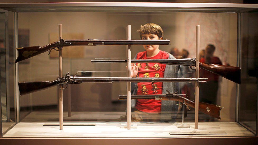 Boy looks at rifles in museum