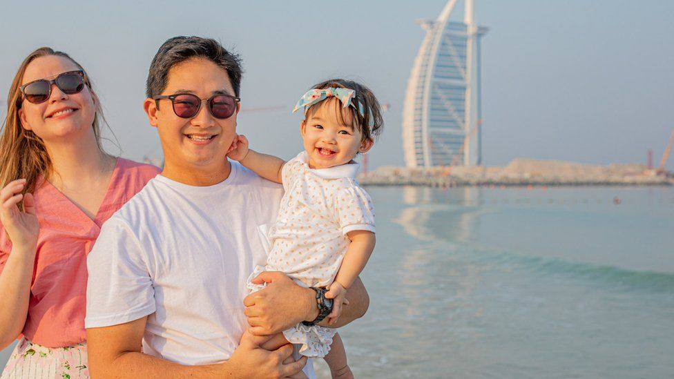 Lygia and Robert with their daughter stand near the Burj al-Arab hotel in Dubai
