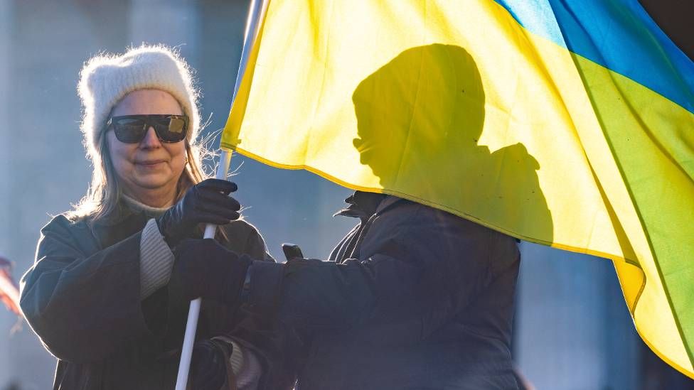 Woman holding Ukrainian flag at vigil to honour the soldiers and civilians who have died