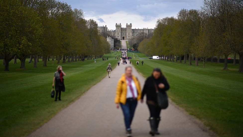 People walk through Windsor Great Park along the Long Walk with Windsor Castle in the background