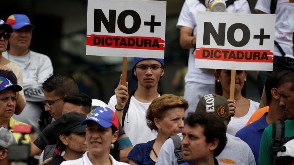 Demonstrators holding signs that read "No more dictatorship" take part in a protest against President Nicolas Maduro government, in Caracas, Venezuela, May 13, 2017