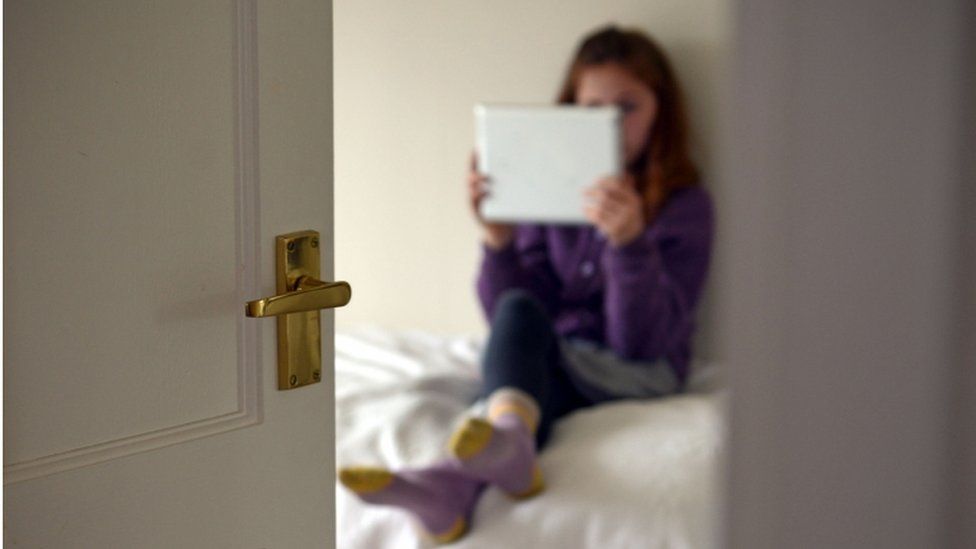 Girl sitting on bed, using a tablet