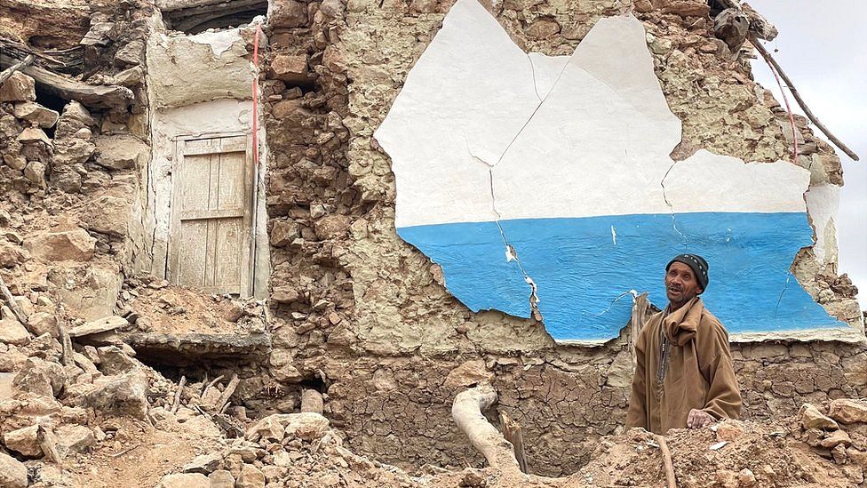 A man stands alongside what remains of a home in the mountainous Moroccan village of Douzrou