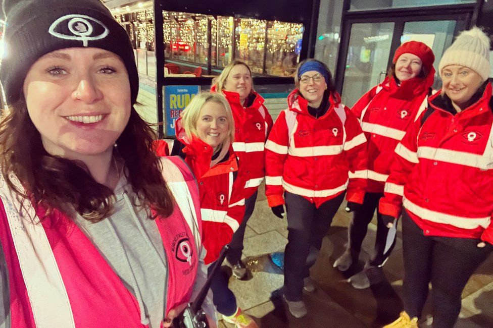 Beth with fellow volunteers wearing red jackets at night in Middlesbrough