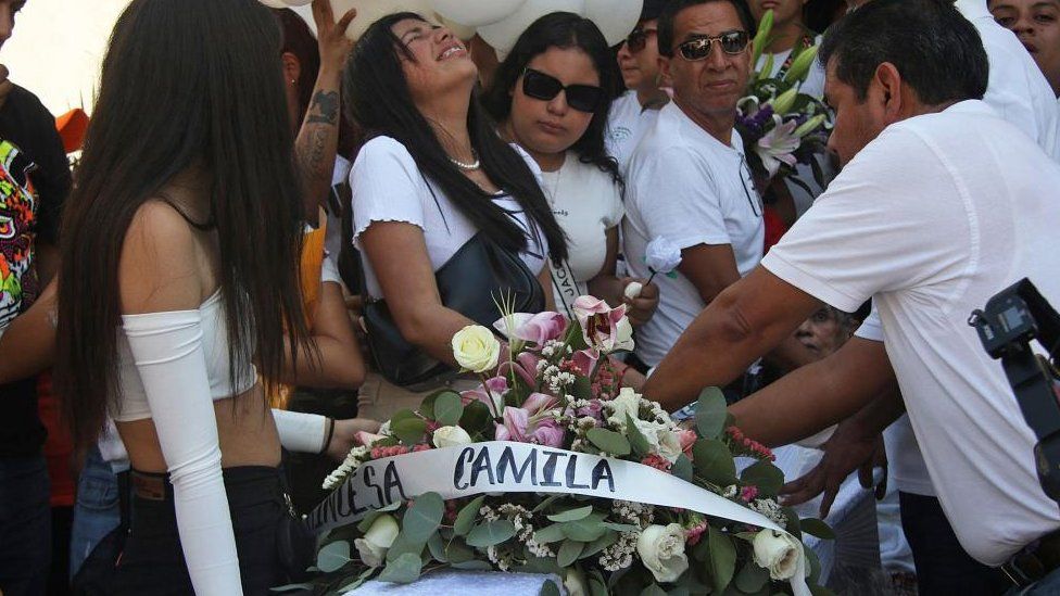 BREAKING NEWS Mourners dressed in white by a coffin