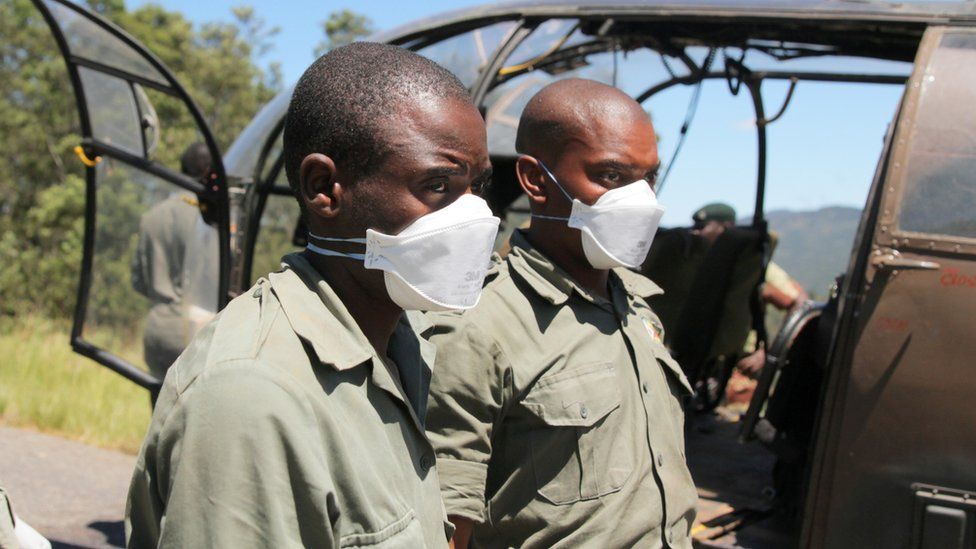 Members of the rescue team wear masks as they prepare to offload a body retrieved from areas flooded in the aftermath of Cyclone Idai in Chimanimani, Zimbabwe, March 21, 2019.