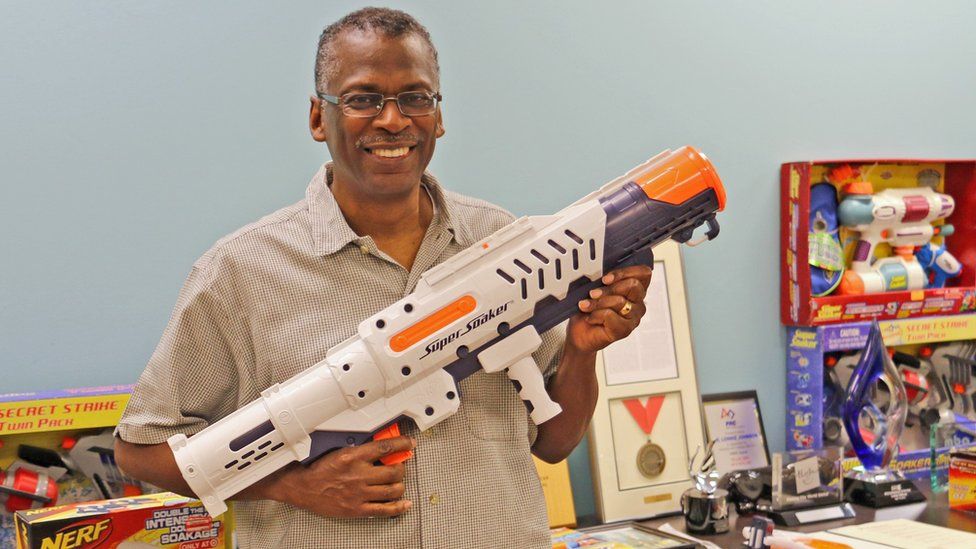 Lonnie Johnson holding some super soaker guns