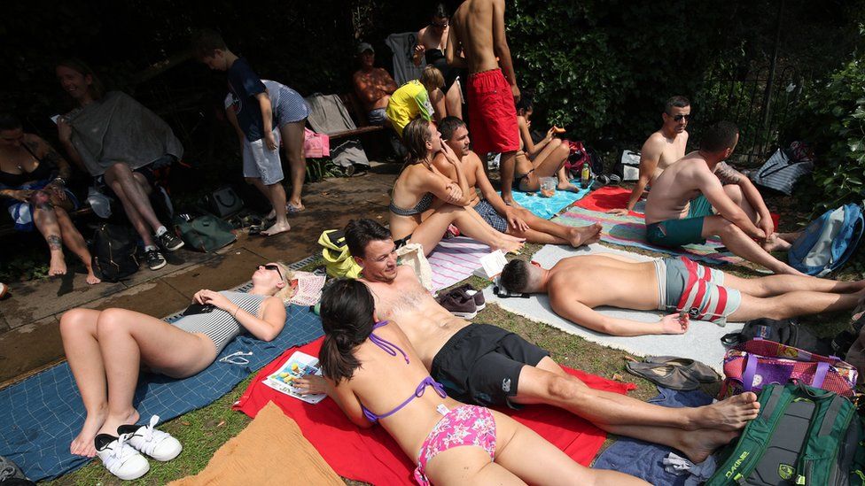 People sunbathing at the mixed bathing pond on Hampstead Heath, London