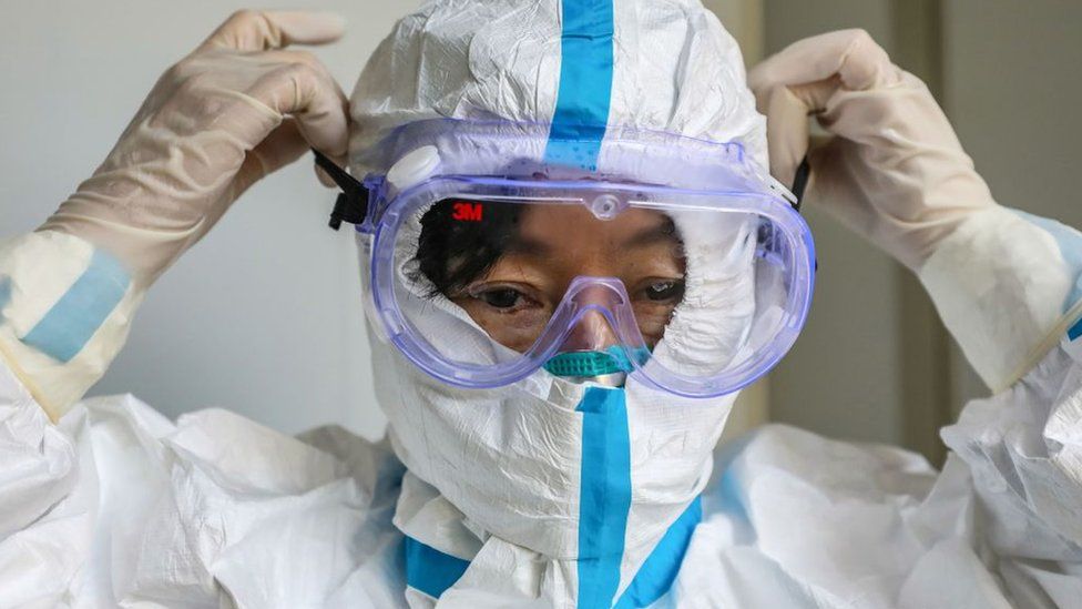 This photo taken on January 30, 2020 shows a doctor putting on a pair of protective glasses before entering the isolation ward at a hospital in Wuhan in China's central Hubei province